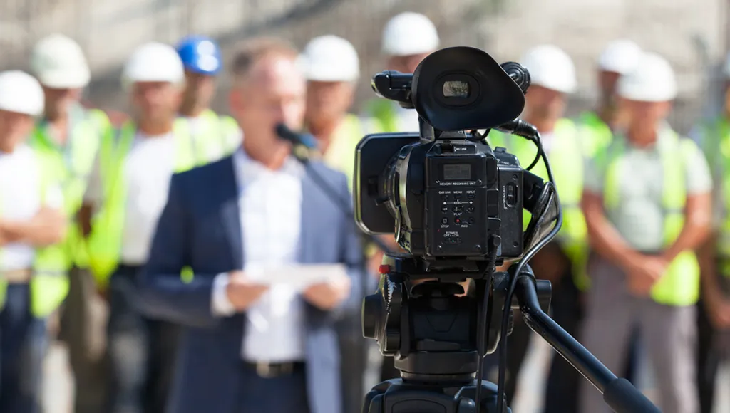 A professional film camera capturing a presenter and team on site